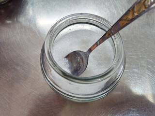Sugar in a jar with a spoon, ready to be used as a condiment.
