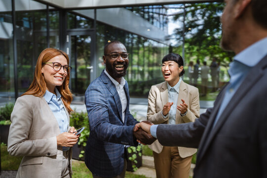 Black and caucasian man handshake agreement in front of company