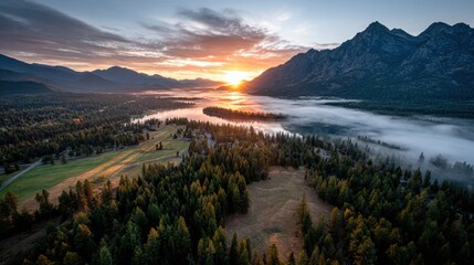 Golden sunlight breaks through clouds, illuminating a lush valley filled with evergreens and a river winding through. Mist lingers over the landscape, creating a serene morning atmosphere.