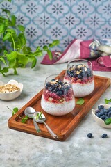 Chia pudding with nut granola, honeysuckle berry puree and whole honeysuckle  berries in...