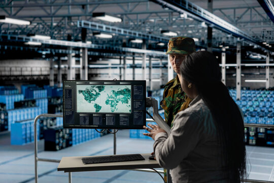 Team of military experts in data center examining mission coverage zones on global mapping software. Army units in server farm confirming strategic priorities using interactive geographic display
