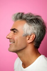 Fototapeta premium A man with timeless elegance and a natural smile. Pink solid background. Creative of style for aging men. Fashionable men's two-block cut haircut - midlife middle eastern man with middle hair.