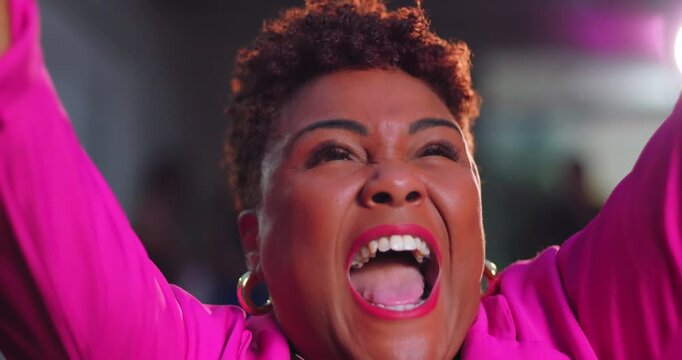 African American woman raising arms and shouting with open mouth, bursting with joy and excitement in vibrant pink blazer and hoop earrings