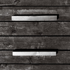 Close-up of textured gray wooden boards with metallic handles casting strong shadows. Industrial...