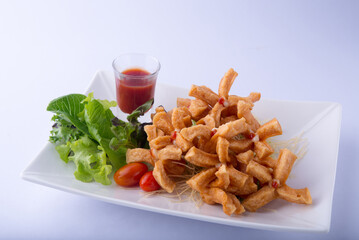 Fried sausage, lettuce, tomatoes, with ketchup on a white plate, white scene