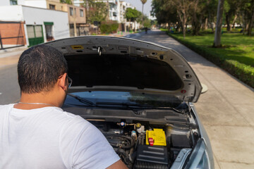 A man is looking at the engine of a car