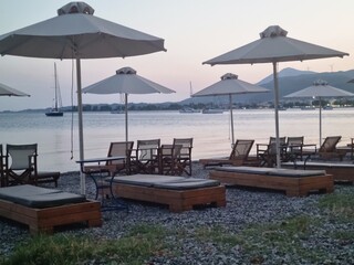 Sunset Beach Scene with Loungers and Umbrellas by the Sea
