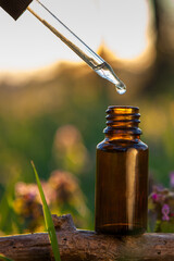 Dropper with Liquid Above Amber Bottle Outdoors