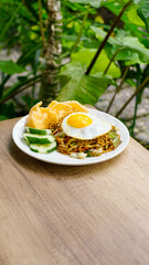 Indonesian Fried Noodles with Sunny Side Up Egg, Crackers, and Cucumber on Plate