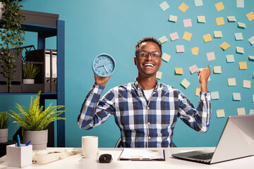 Happy businessman with a clock in hand, celebrating for finishing project presentation before...