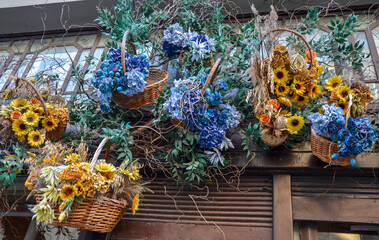 Wicker baskets artistically arranged on wall, showcasing vibrant sunflowers and hydrangeas...