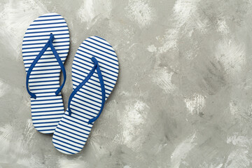 Striped blue flip flops on concrete background, top view