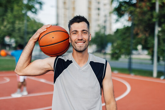 Basketball player holding ball smiling on court