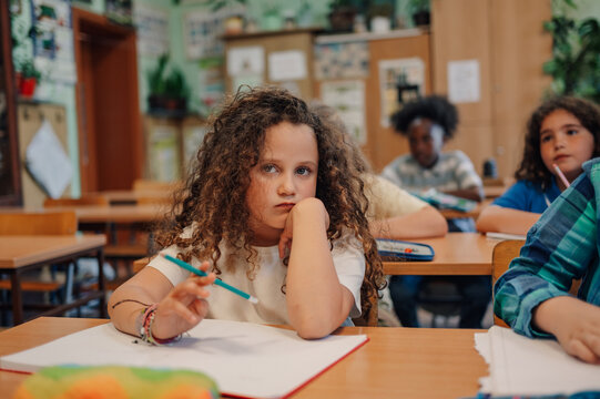 Bored elementary school student during class resting head on hand