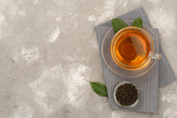 Cup of tea with dry and fresh leaves on concrete background, top view