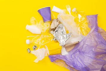 Bag with unsorted waste on color background, top view