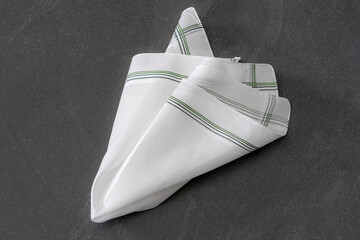 Classic men's handkerchief with striped pattern on dark stone background.