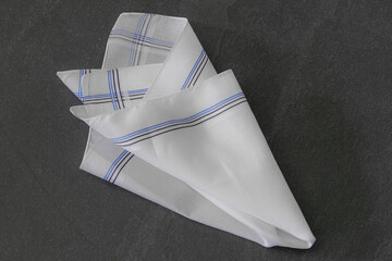 Classic men's handkerchief with striped pattern on dark stone background.