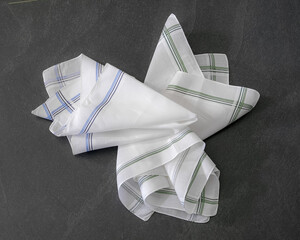 Classic men’s handkerchiefs with striped pattern on dark stone background.