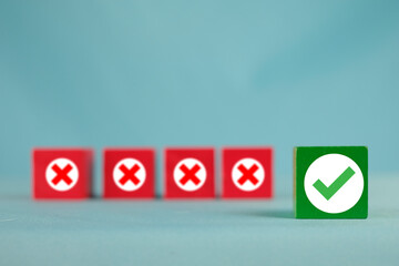 A green block with a checkmark in focus, with red X mark blocks blurred in the background. Concept...