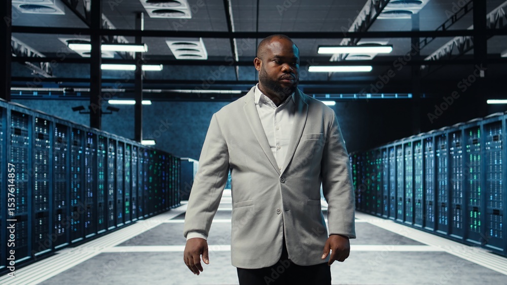 Poster employee walking in data center with blinking lights on rigs showing system activity. it professiona