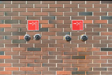 Two fire cranes are mounted on a textured brick wall in a multi-storey building