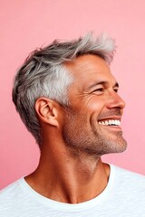 Fototapeta premium Trendy men's classic short back and sides haircut - midlife white man with grey hair. Pink solid background. Idea of style for aging men. A studio glamour portrait of a confident man.