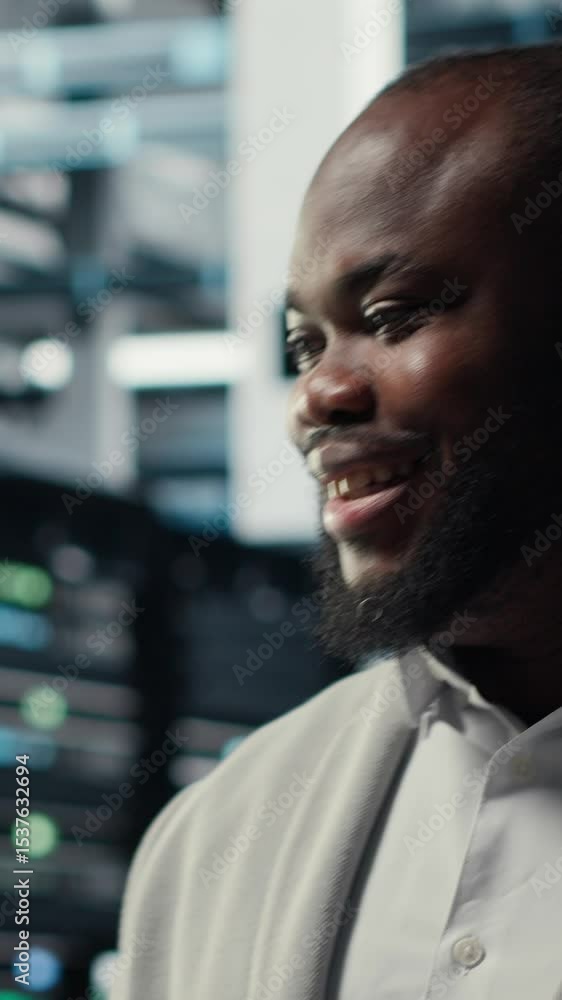 Poster vertical video smiling server room engineer performing maintenance on server racks using software on