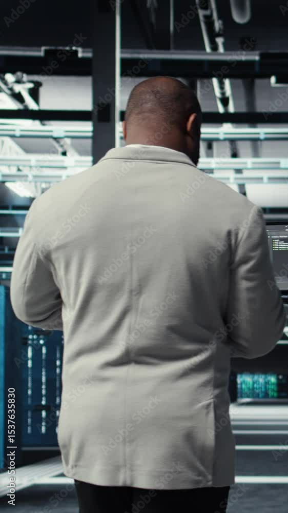 Poster vertical video data center technician using laptop to manage software updates for system stability. 