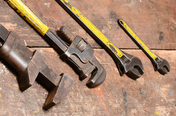 Old wrenches on a worn wooden workbench, showcasing traditional tools