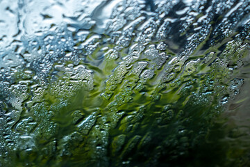 Raindrops on glass distorting a green landscape. A visual representation of nature's interaction...