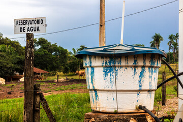 Water reservoir in rural area, Brazil. Plastic tank with Water Reservoir sign in portuguese....