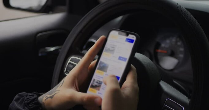 Man chooses to buy car on site. Looking at used vehicle to buy on smartphone app. Close Up. Screen is blurred. 4K UHD. 