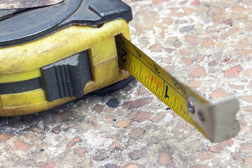 Close-up photo of an aged, rusted yellow measuring tape on a textured surface