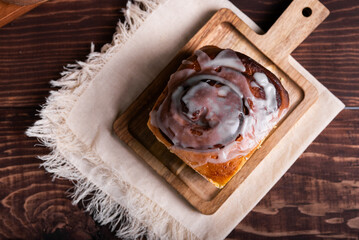 Sweet cinnamon roll on a wooden board on a rustic table