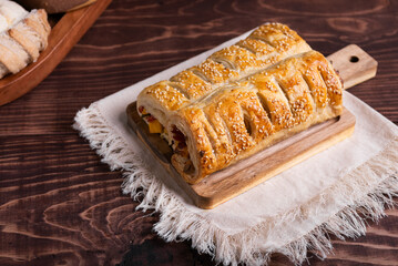 A golden puff pastry with tasty filling, sprinkled with sesame seeds.