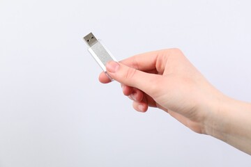 Man with modern flash drive on light grey background, closeup. Space for text