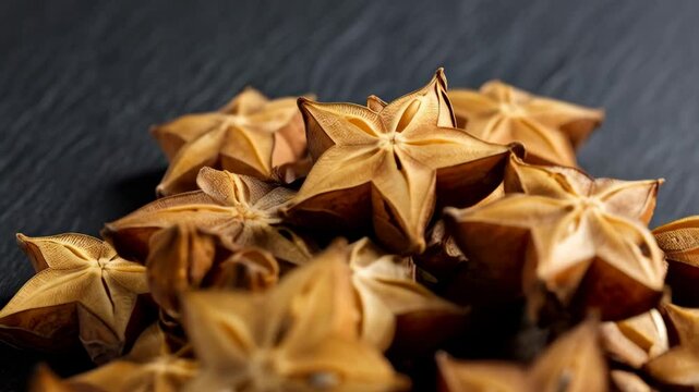 Pile of dried Sacha Inchi seed pods, a tropical healthy snack, on a dark surface. A close up shows the star-shaped seeds in detail.