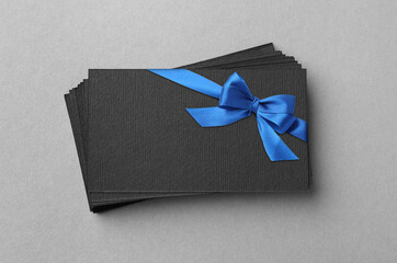 Blank gift card with blue bow on light grey background, top view. Mockup for design