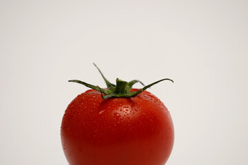 Ripe tomato with water drops, side view on white background. Clean, simple layout great for food advertising and product design.
