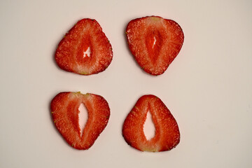 Four strawberry halves arranged on a white background. Clean top view for dessert, fruit, or...