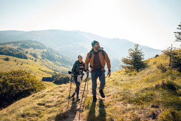 Couple hiking on a mountain trail on a sunny day