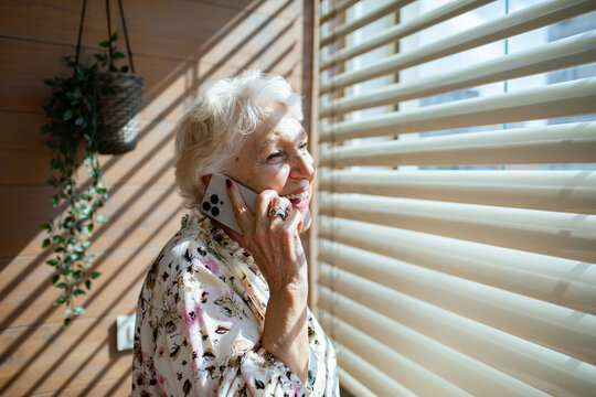 Senior woman talking on the phone at home with a happy smile - Powered by Adobe