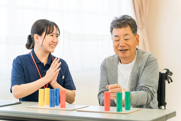 Fototapeta premium 介護施設・リハビリ施設で働く作業療法士の職員とリハビリをするシニア男性 