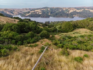 Aerial view of a fallen telephone pole in a grassy field, with a San Pablo Reservoir and rolling...