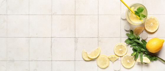 Glass of fresh lemonade with mint and ice cubes on white tile background