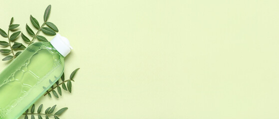 Bottle of micellar water and leaves on green background