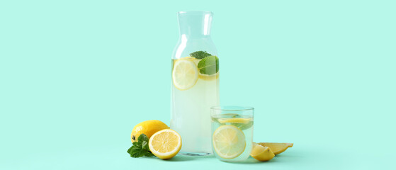 Glass and bottle of fresh lemonade with mint on turquoise background