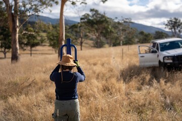 female farmer driving steel posts with a post driver on a farm putting up a steel post fence with high tensile wire in australia women in agriculture in spring