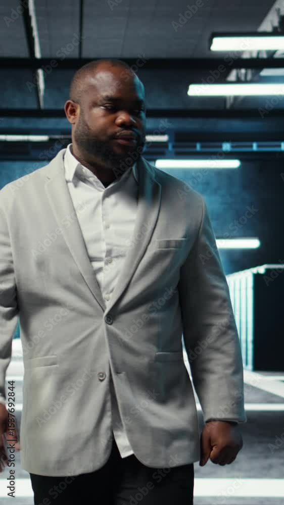 Poster vertical video employee walking in data center with blinking lights on rigs showing system activity.